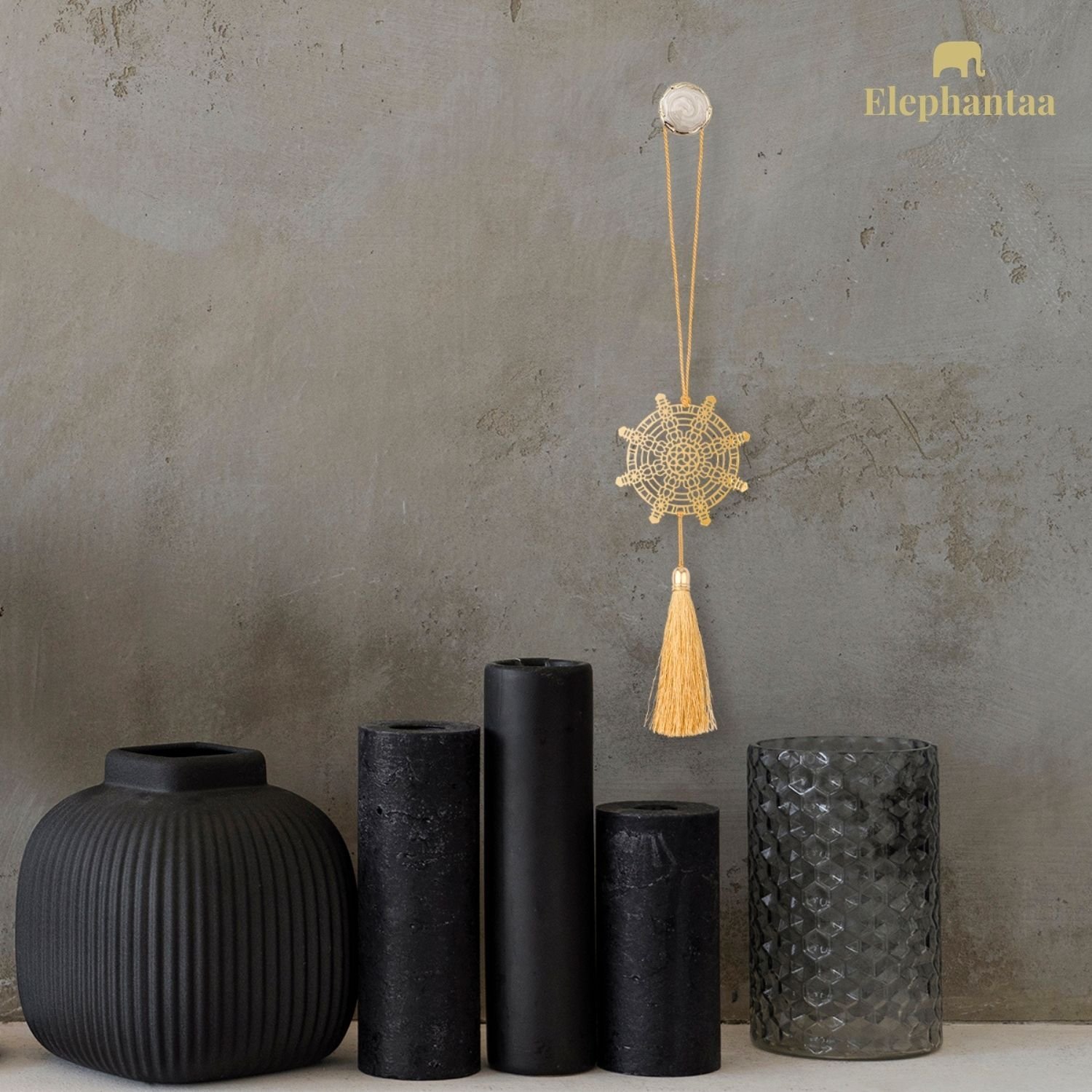 Brass Dharma Chakra hanging décor with golden tassel on modern textured wall