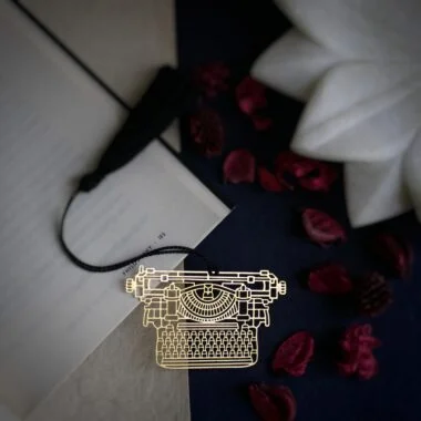 Typewriter design brass bookmark with tassel on open book – handcrafted by ELEPHANTAA