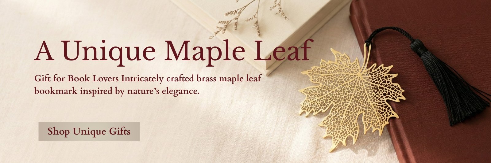 Intricately crafted brass maple leaf bookmark resting on a red hardcover book.