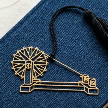 Charkha brass bookmark on blue book with khadi thread spool, Indian heritage inspired gift