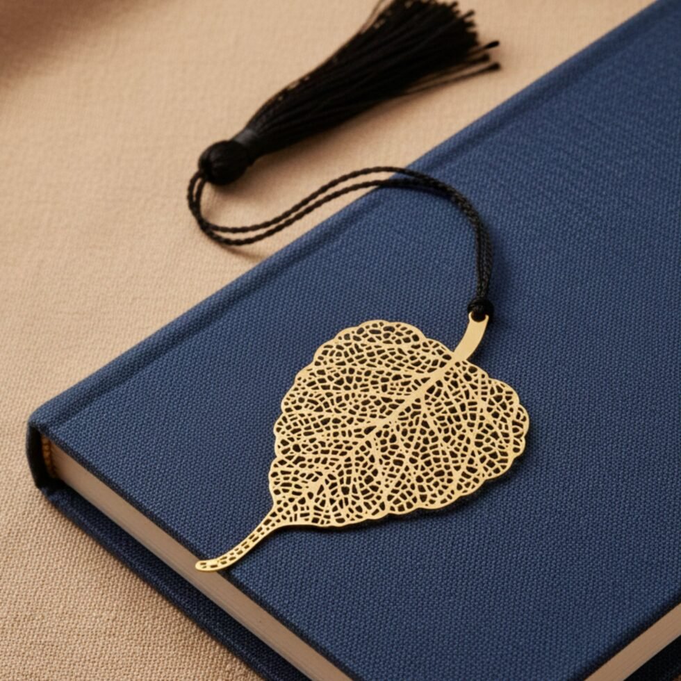 Bodhi leaf brass bookmark placed on navy blue book with black tassel