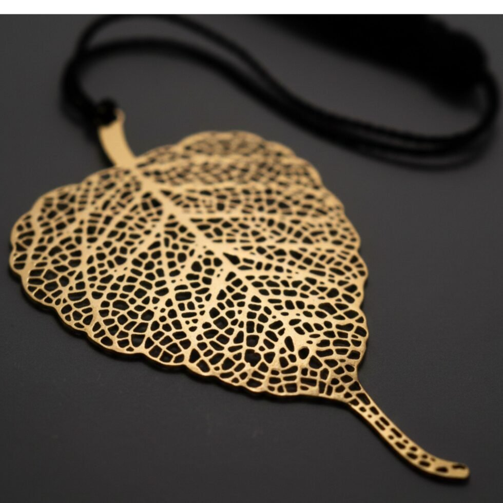 Bodhi leaf brass bookmark with black tassel placed on dark background