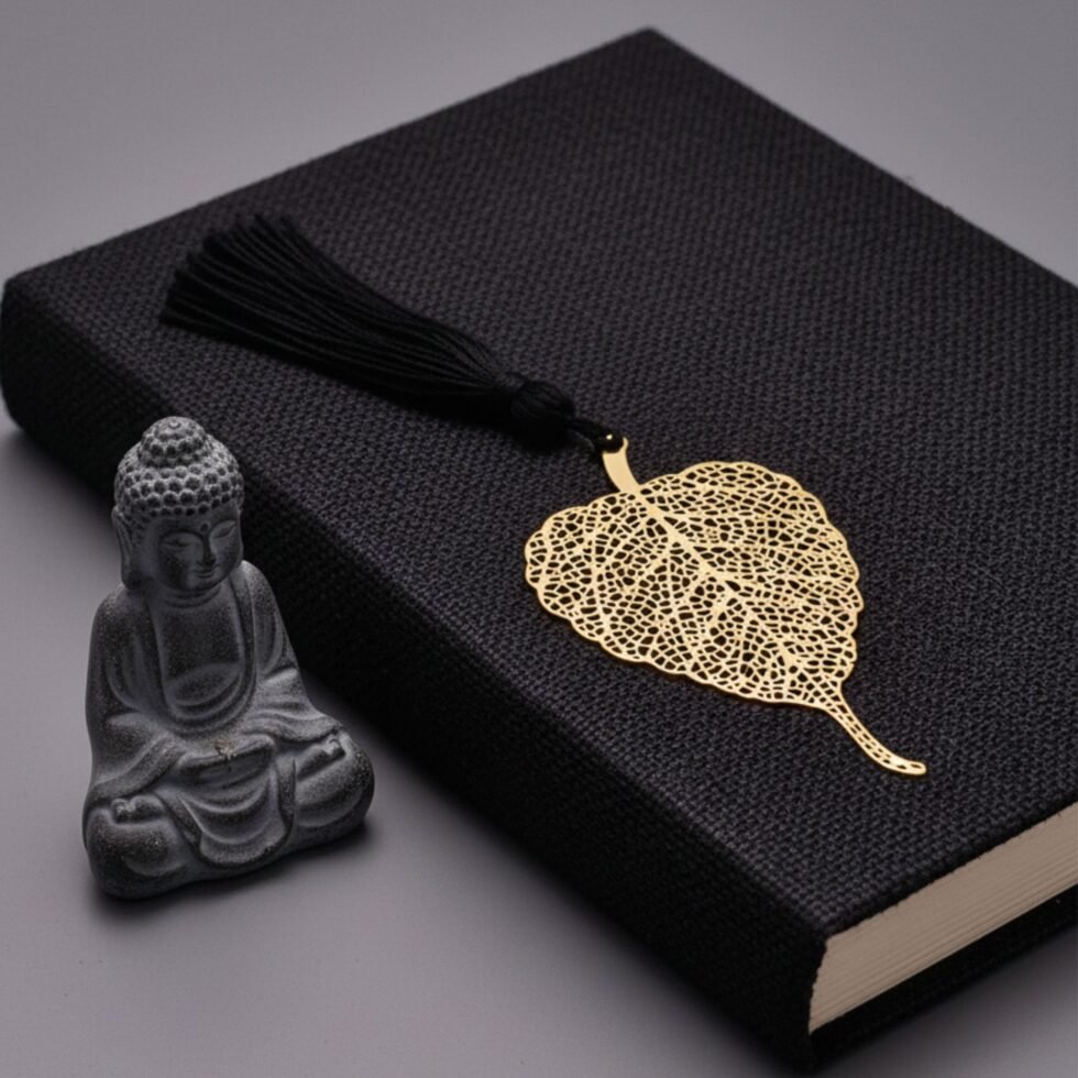 Bodhi leaf brass bookmark placed on book with Buddha statue background