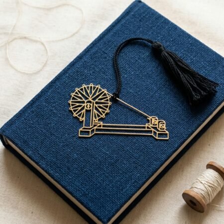 Charkha brass bookmark on blue book with khadi thread spool, Indian heritage inspired gift