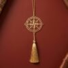 Gold polished brass compass hanging decor with tassel displayed on a barn red textured background in elegant minimalist styling