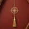 Gold polished brass compass hanging decor with tassel displayed on a barn red textured background in elegant minimalist styling