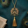 Gold plated brass yoga hanging decor on teal jute fabric with peacock feathers and linen accents.